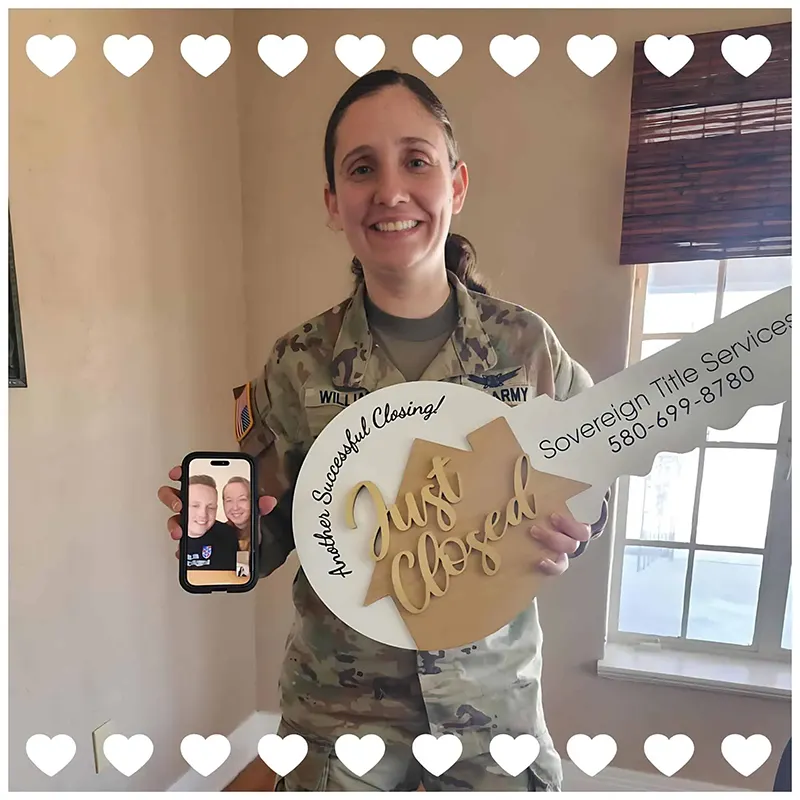 A soldier in uniform holding a “Just Closed” key sign after closing on a home with Brittany McConnell